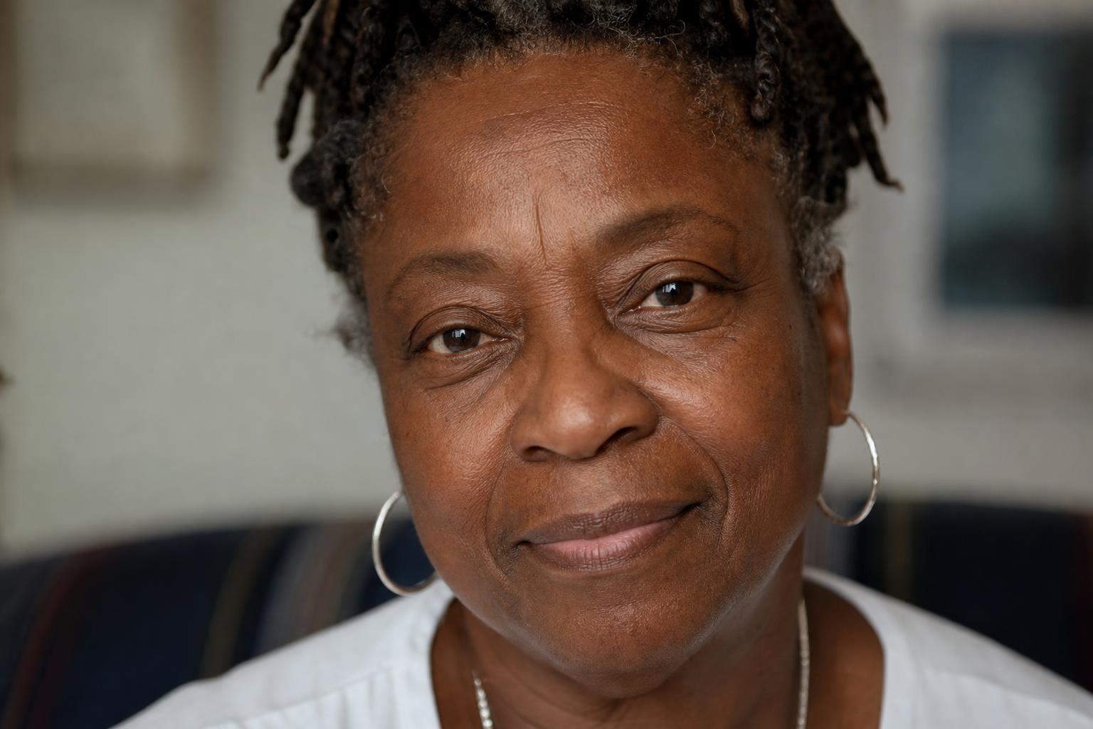 A deep-complexioned Black woman in her sixties looking directly into the camera