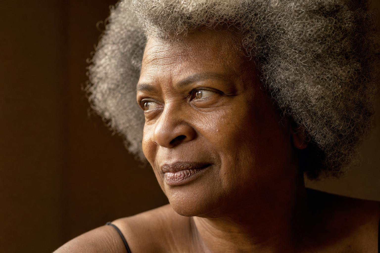 A Black woman in her late sixties with a natural grey afro, golden light